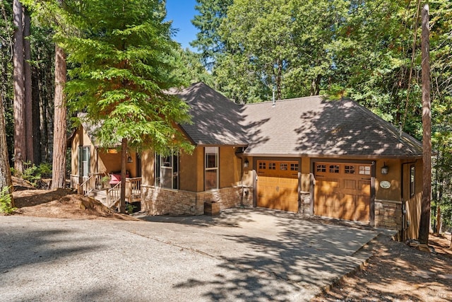 rustic home with stone siding, driveway, an attached garage, and stucco siding