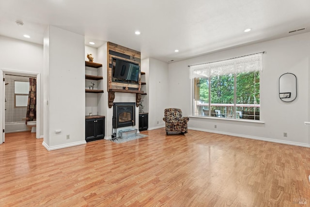 unfurnished living room with a wood stove, light hardwood / wood-style flooring, and a large fireplace