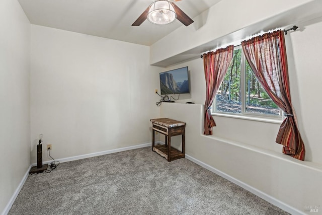 carpeted spare room featuring a ceiling fan and baseboards