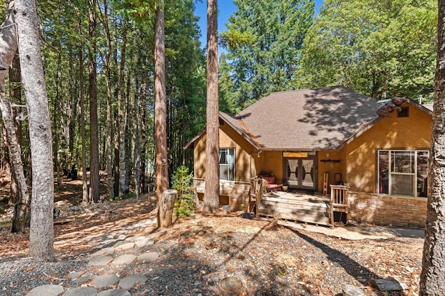 view of front of home with stone siding, french doors, and a shingled roof