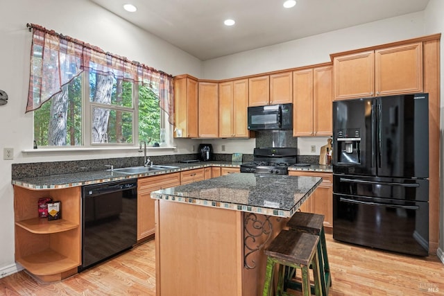 kitchen featuring light hardwood / wood-style flooring, sink, black appliances, a breakfast bar area, and a kitchen island