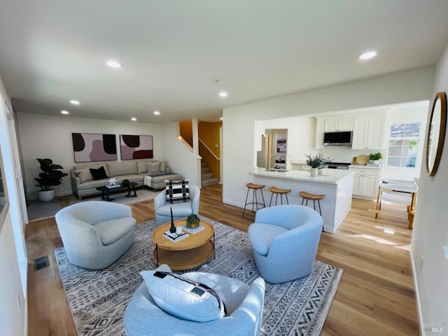 living room with light hardwood / wood-style floors and sink