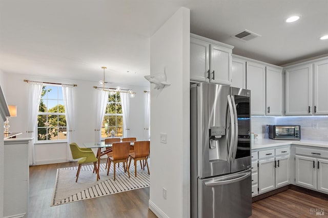 kitchen featuring tasteful backsplash, dark hardwood / wood-style flooring, hanging light fixtures, stainless steel refrigerator with ice dispenser, and white cabinets