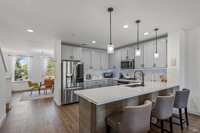 kitchen featuring pendant lighting, stainless steel appliances, dark hardwood / wood-style flooring, sink, and a breakfast bar