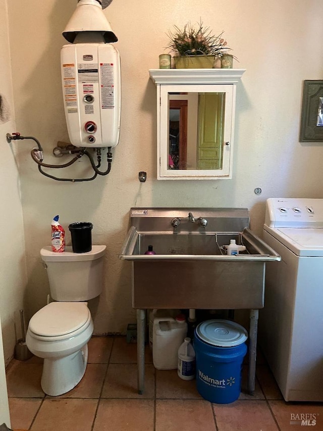 bathroom featuring water heater, washer / dryer, toilet, sink, and tile patterned floors