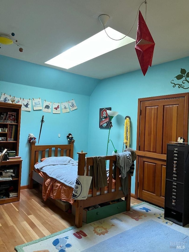 bedroom with light wood-type flooring and vaulted ceiling