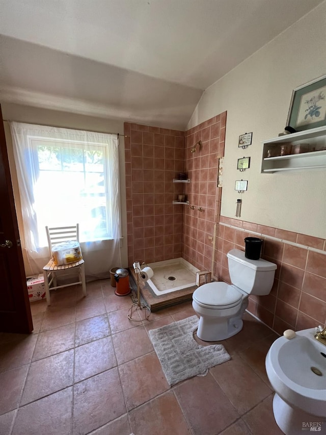 bathroom featuring tile walls, a tile shower, lofted ceiling, toilet, and a bidet