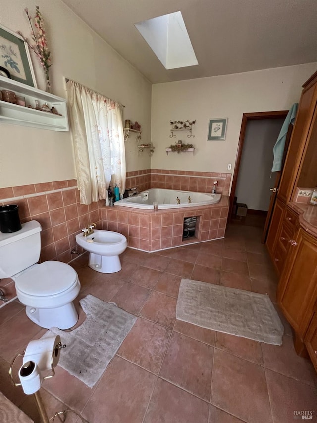 bathroom featuring tiled bath, a skylight, toilet, a bidet, and tile patterned floors