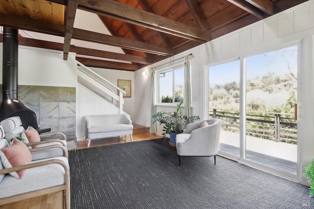 sunroom / solarium with lofted ceiling with beams, a wood stove, and wooden ceiling