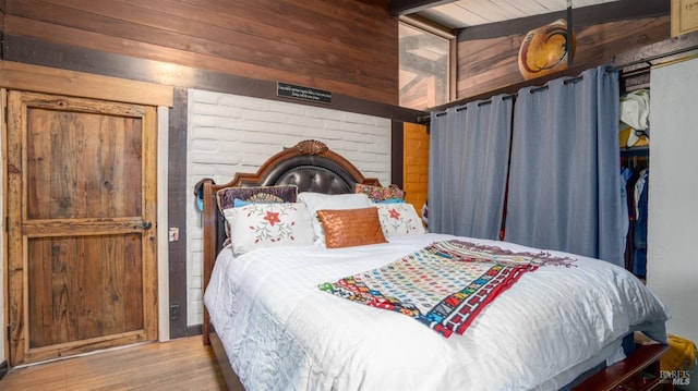 bedroom with wood walls, wooden ceiling, and light wood-type flooring