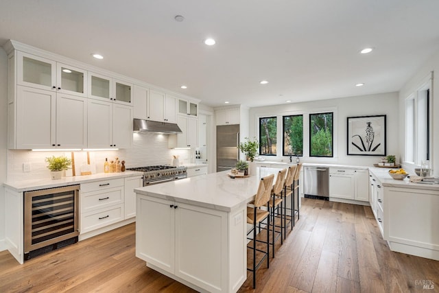 kitchen featuring a kitchen island, wine cooler, a kitchen bar, light wood-type flooring, and premium appliances