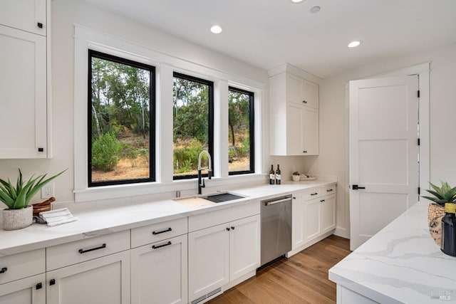 kitchen featuring stainless steel dishwasher, sink, light wood-type flooring, and white cabinetry