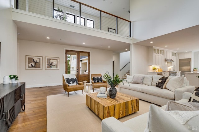 living room featuring a wealth of natural light, a high ceiling, and light wood-type flooring