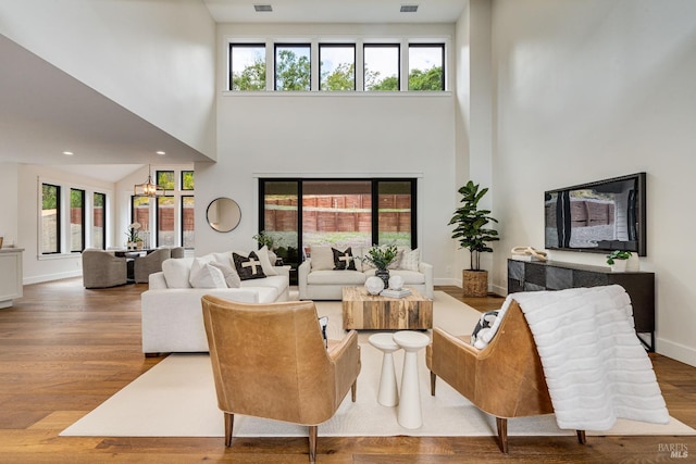 living room with a wealth of natural light, wood-type flooring, and a high ceiling