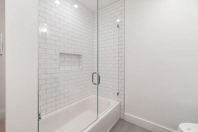 full bathroom with enclosed tub / shower combo, toilet, and baseboards