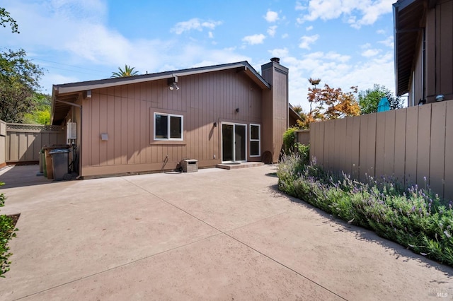 rear view of house featuring a patio area, a chimney, and fence