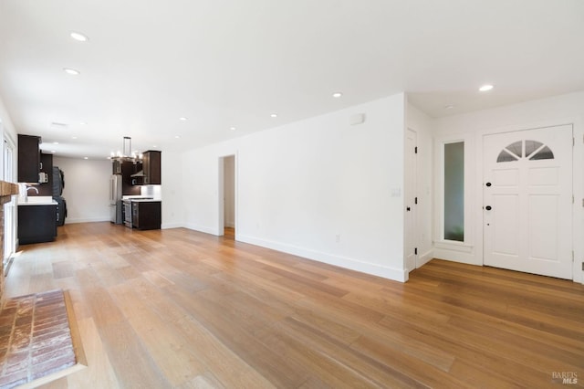 unfurnished living room featuring light wood-style floors, recessed lighting, a notable chandelier, and baseboards