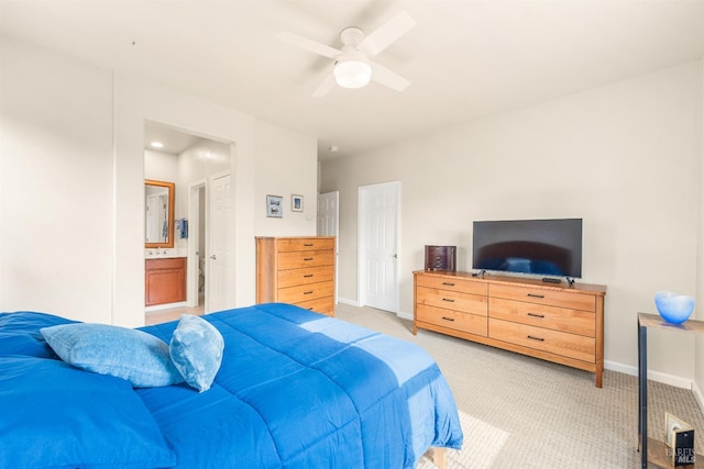 bedroom featuring light carpet, ensuite bathroom, and ceiling fan