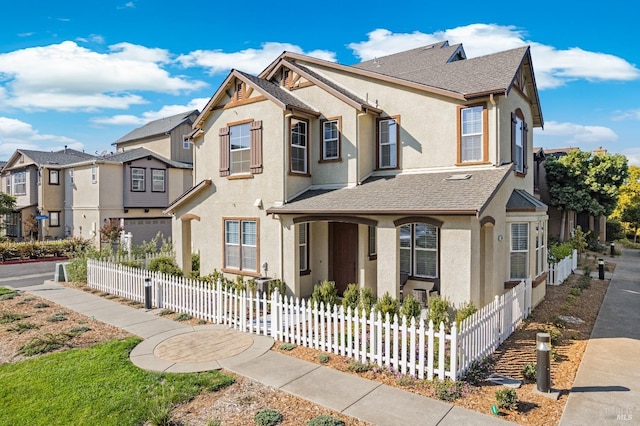 view of front of house with a shingled roof, a fenced front yard, stucco siding, and a residential view