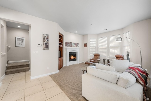 living room with baseboards, a warm lit fireplace, light carpet, recessed lighting, and visible vents