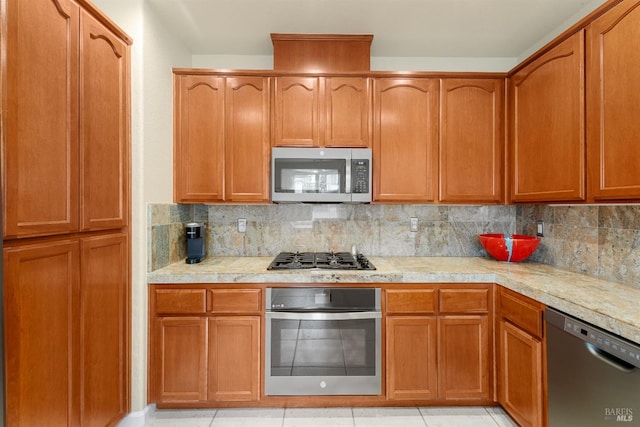 kitchen featuring tasteful backsplash, stainless steel appliances, and light tile patterned floors