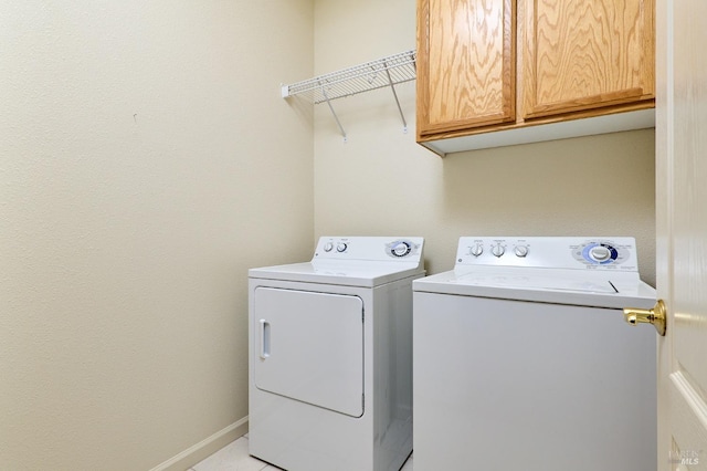 clothes washing area with washing machine and clothes dryer and cabinets