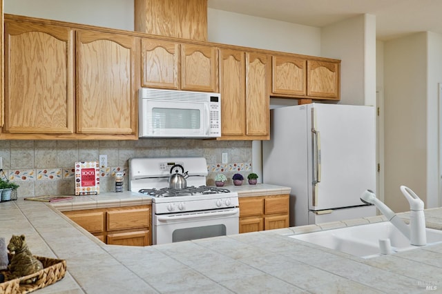 kitchen featuring white appliances, tile countertops, backsplash, and sink