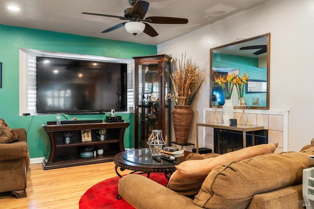 living room with wood-type flooring, a fireplace, and ceiling fan