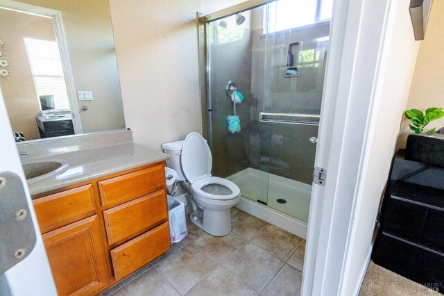 bathroom featuring tile patterned flooring, vanity, toilet, and walk in shower