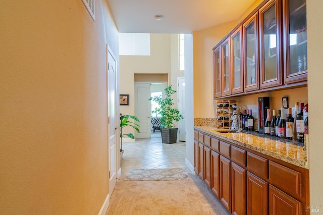 bar with light stone counters, sink, and light colored carpet