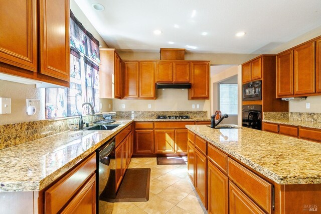 kitchen featuring a kitchen island with sink, sink, black appliances, and light stone counters