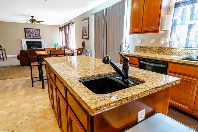 kitchen featuring light stone counters, sink, light tile patterned floors, black dishwasher, and a kitchen island