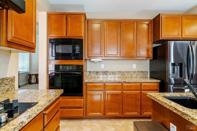 kitchen with light stone countertops, sink, light tile patterned floors, and black appliances