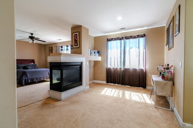 carpeted living room featuring ceiling fan and a multi sided fireplace