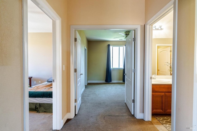 hallway with light colored carpet and sink