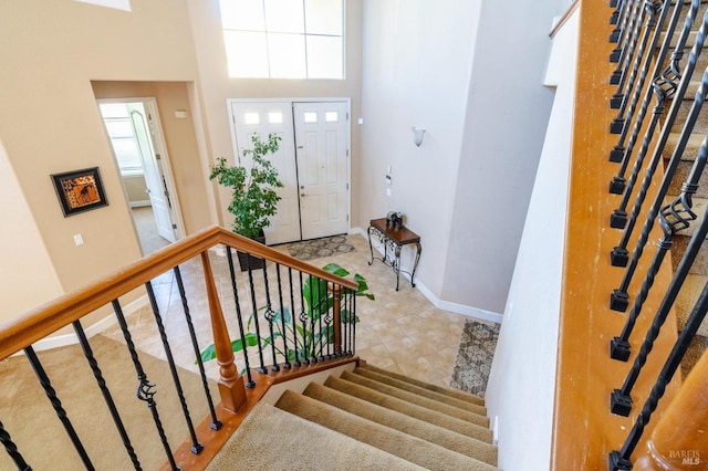 stairs with tile patterned flooring and a high ceiling