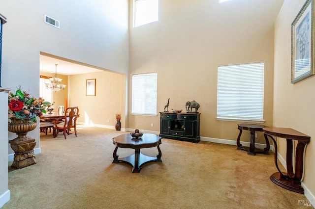 carpeted living room with a towering ceiling and a chandelier