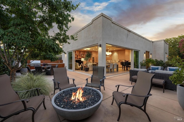 patio terrace at dusk with an outdoor living space with a fire pit