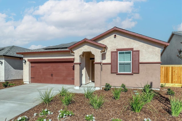 view of front of property with a garage, fence, driveway, roof mounted solar panels, and stucco siding