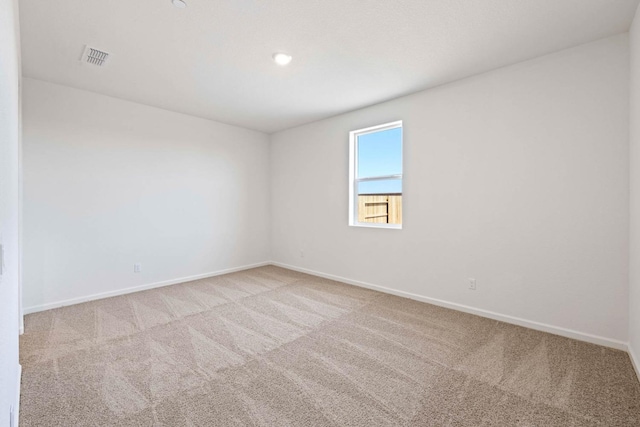 spare room featuring carpet floors, visible vents, and baseboards