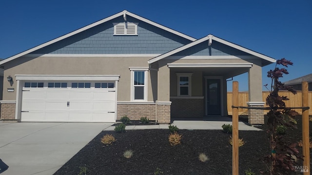 view of front of home featuring stucco siding, concrete driveway, an attached garage, fence, and stone siding