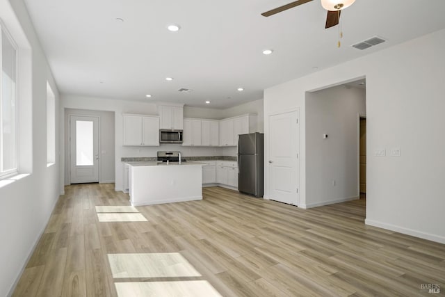 kitchen with a center island with sink, light hardwood / wood-style flooring, stainless steel appliances, and white cabinets