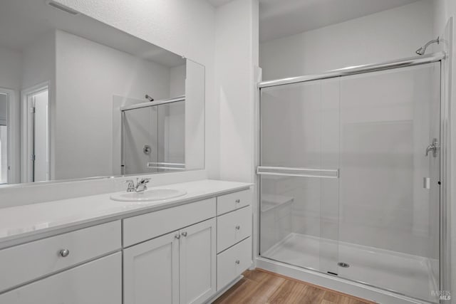 bathroom with visible vents, a shower stall, vanity, and wood finished floors