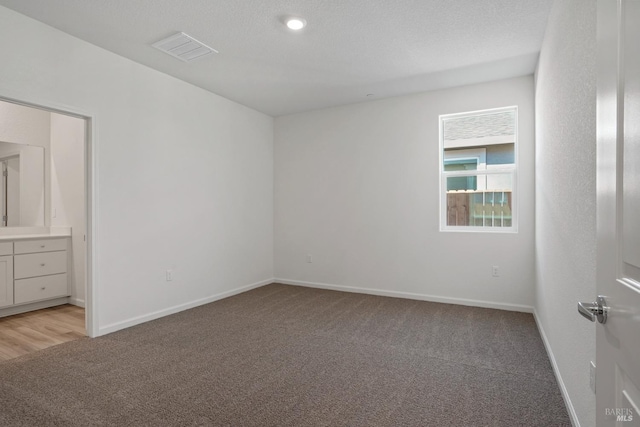 unfurnished bedroom with light carpet, visible vents, baseboards, and a textured ceiling