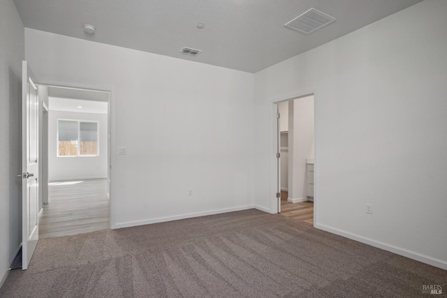 carpeted spare room featuring visible vents and baseboards