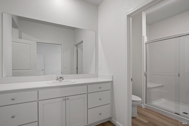 bathroom with walk in shower, toilet, wood-type flooring, and vanity