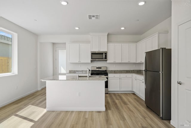 kitchen featuring light hardwood / wood-style flooring, stainless steel appliances, light stone counters, and white cabinetry