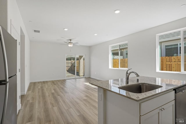 kitchen featuring visible vents, appliances with stainless steel finishes, open floor plan, a sink, and light wood-type flooring