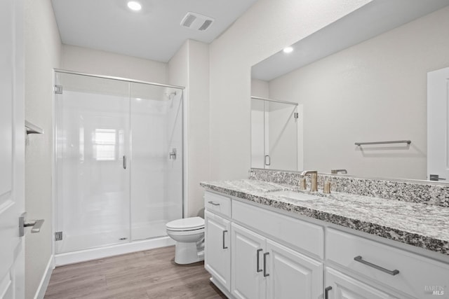 full bathroom featuring toilet, wood finished floors, visible vents, and a stall shower