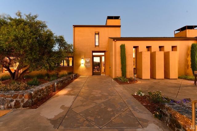 view of front of home with a chimney and stucco siding